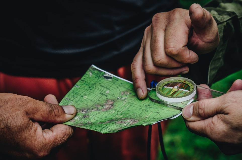 two person holding map and clear compass